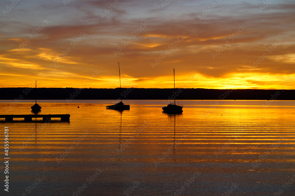 a beautiful golden sunset on lake Ammersee with sailing boats resting on the water (Herrsching in Germany)