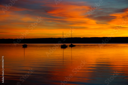 a breathtaking burning sunset on lake Ammersee with sailing boats resting on the water (Herrsching am Ammersee in Germany) © Julia