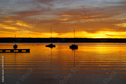 a beautiful golden sunset on lake Ammersee with sailing boats resting on the water (Herrsching in Germany)