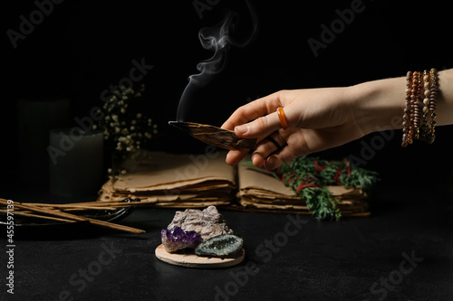 Hand with Palo Santo, minerals and incense on dark background