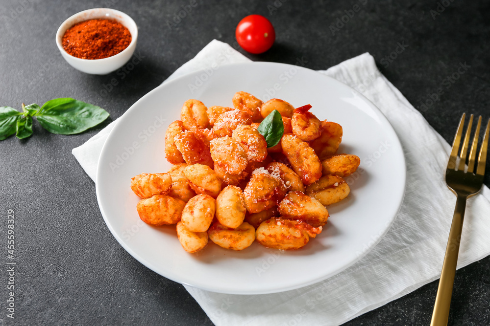 Delicious gnocchi with tomato sauce in plate on dark table Delicious gnocchi with tomato sauce in plate on dark table