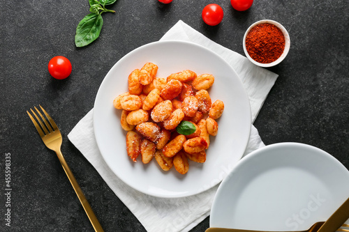 Delicious gnocchi with tomato sauce in plate on dark table photo