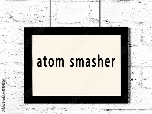 фотографія Black frame hanging on white brick wall with inscription atom smasher