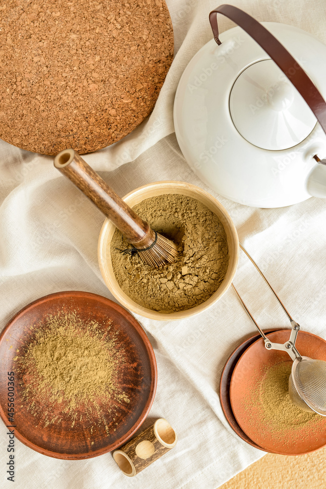 Composition with powdered matcha tea, chasen and teapot on fabric background, closeup Composition with powdered matcha tea, chasen and teapot on fabric background, closeup