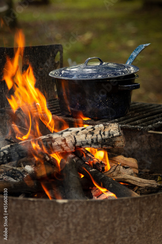 a campfire with a blue pot cooking