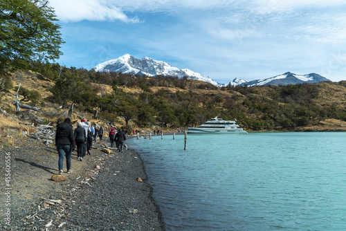 Fototapet Tourists walking on the edge of the lake on an excursion through Patagonia