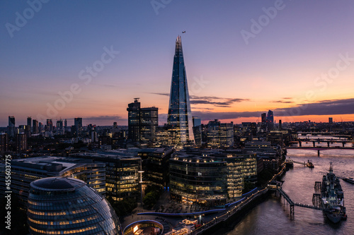 Aerial view of financial tower surrounded by small buildings in the beautiful city of London on a cloudy sunset evening with blue sky