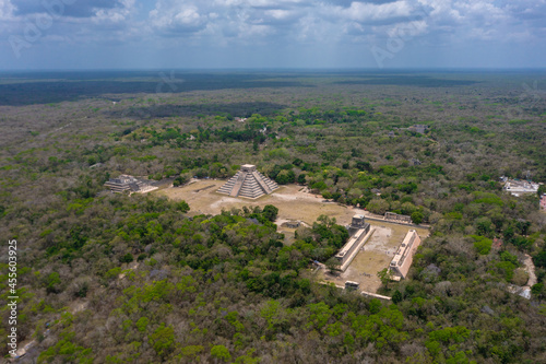 Aerial view of the beautiful Chicen Itza and Mayan Pyramid in Mexico surrounded with ground and greenery with ocean under cloudy sky during day photo