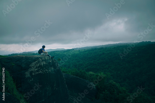 treker on mountain top with large green forest background