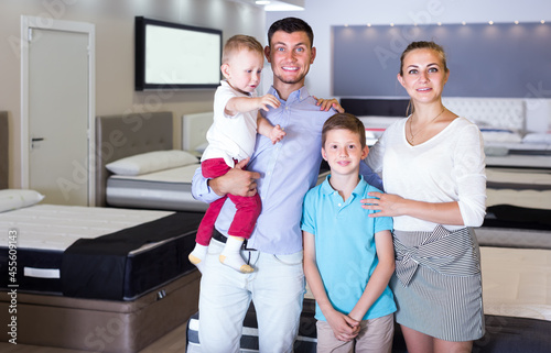 Portrait of family visiting furniture salon in search of new mattress for purchase