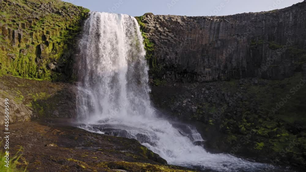 Waterfall over unique rock formations with lush green grass (Slow Motion) Waterfall over unique rock formations with lush green grass (Slow Motion)