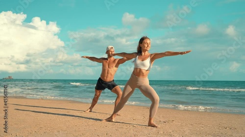 Couple training - Young sports couple doing acro yoga exercises on sand beach. Couple making yoga exercises on sand. fitness, sport, people and lifestyle concept, Caucasian fitness model.