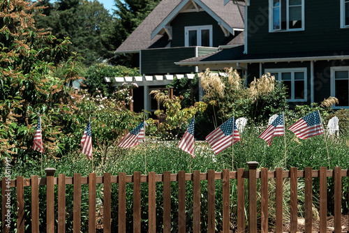 American Flags on wooden fence in front of a house.