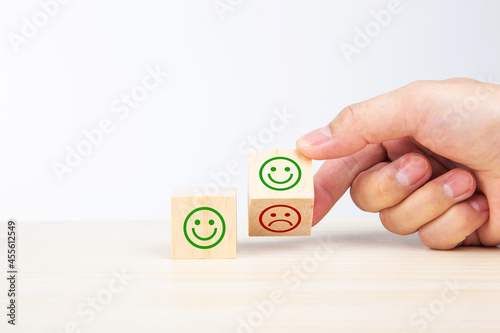 Hand turning a wooden block With Happy and Unhappy Face