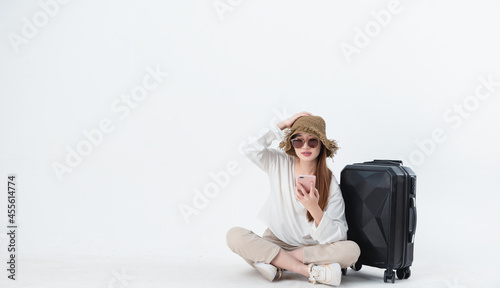 Portrait of smiling asian woman wearing sunglasses and hat with suitcase on grey background studio.Concept to traveling.