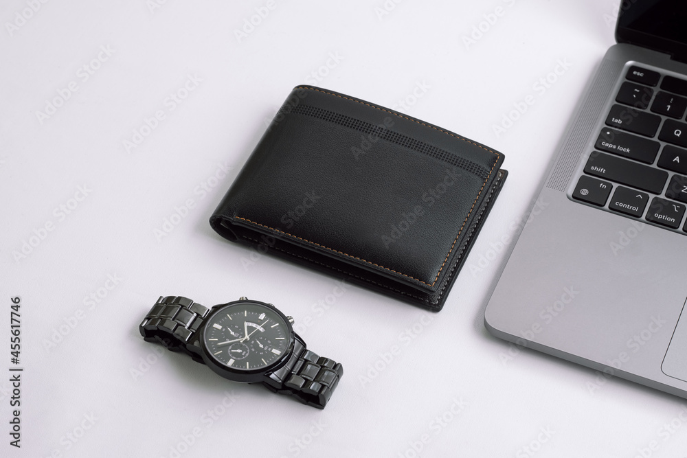 Fashionable black leather men's wallet with watch and laptop on white office desk, white table. Work desk view. Top angle work desk. Flat lay work desk Fashionable black leather men's wallet with watch and laptop on white office desk, white table. Work desk view. Top angle work desk. Flat lay work desk