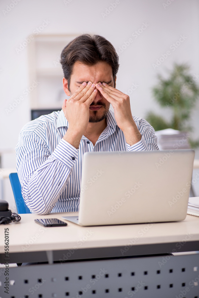 Young male employee and too much work in the office Young male employee and too much work in the office