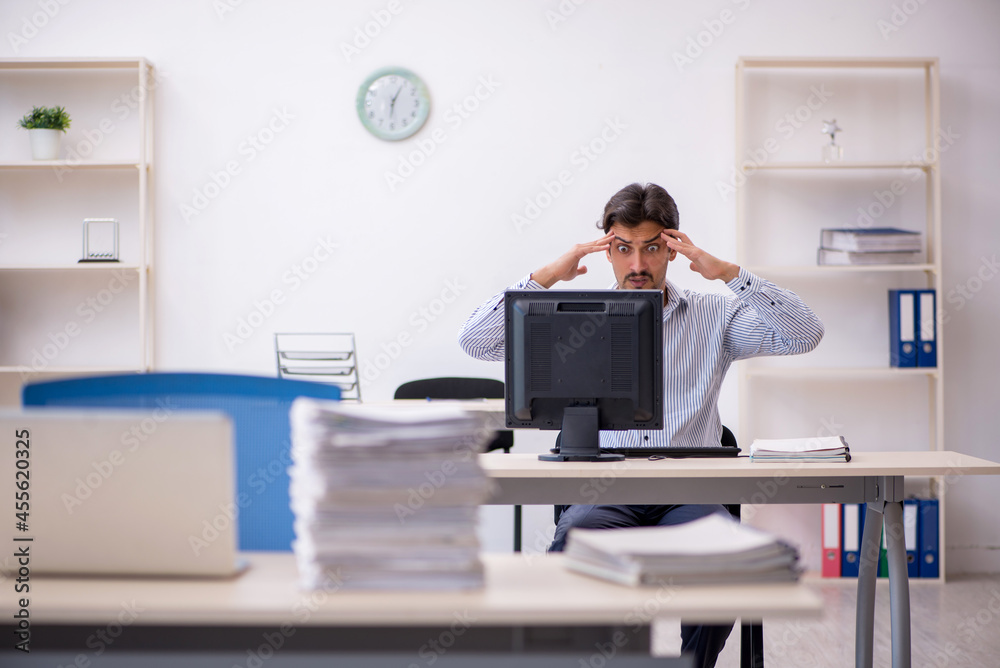 Young male employee and too much work in the office Young male employee and too much work in the office