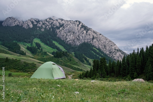 Tent with rocky mountains and cloudy sky on. background. Nature background. Wilderness background. Adventure travel concept. Komirshi gorge in Kazakhstan.