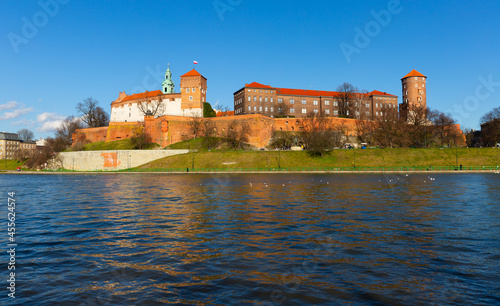 Medieval fortified architectural complex of Wawel Castle and bell tower of Archcathedral Basilica on banks of Vistula river in springtime, Krakow, Poland. photo