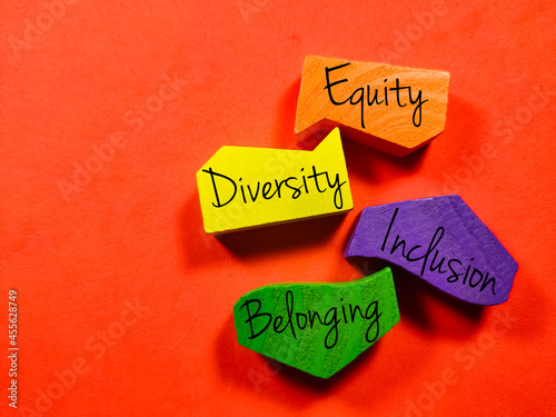 Business concept.Text Equity Diversity Inclusion Belonging with colored wooden block isolated on a red background photo