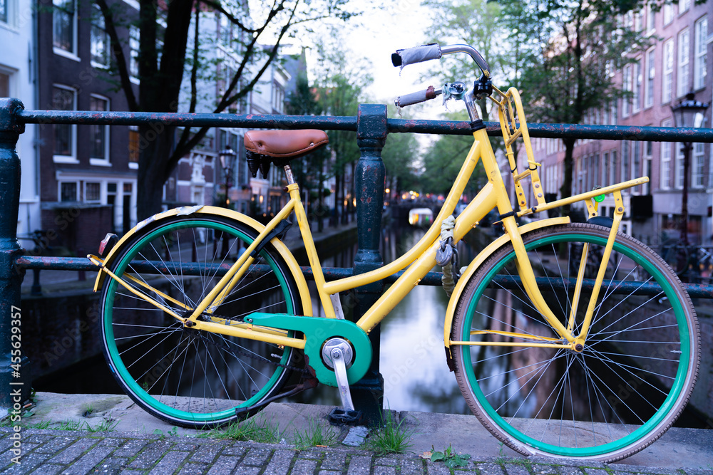 Bright yellow and green bicycle locked to railing on city bridge