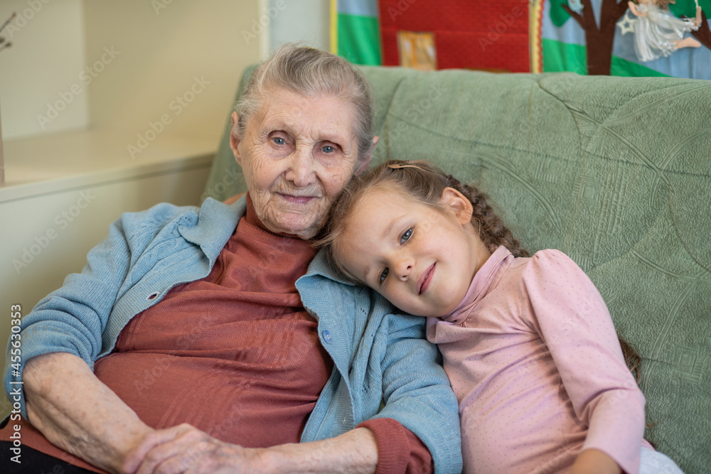 Portrait of an old woman and a little girl, grandmother hugs her granddaughter, family ties, old age and youth, 90 years, wrinkles on an old face, beautiful old age, a woman and a child. Portrait of an old woman and a little girl, grandmother hugs her granddaughter, family ties, old age and youth, 90 years, wrinkles on an old face, beautiful old age, a woman and a child.