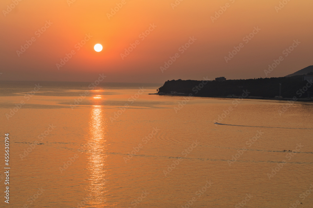 Beautiful cloudless sunset on the sea with sunlight reflected in the water