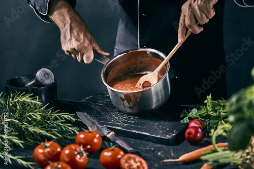 Fototapeta Naklejka Na Ścianę i Meble -  Unrecognizable chef cooking vegetable soup in kitchen