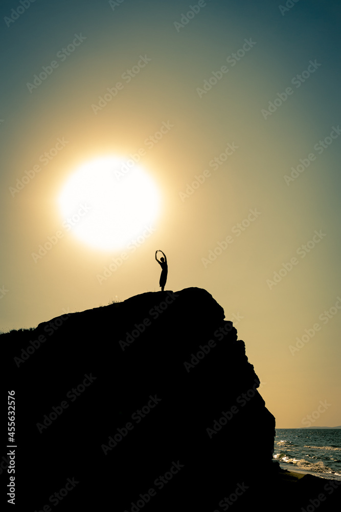 the girl stands on a rock in the backlight