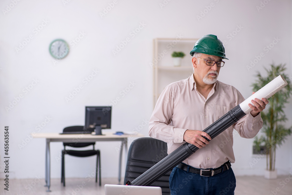 Old male architect working in the office Old male architect working in the office