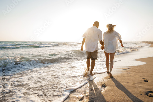 Young beautiful couple walking on beach near sea photo