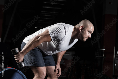 Male bodybuilder engaged with dumbbells in the gym