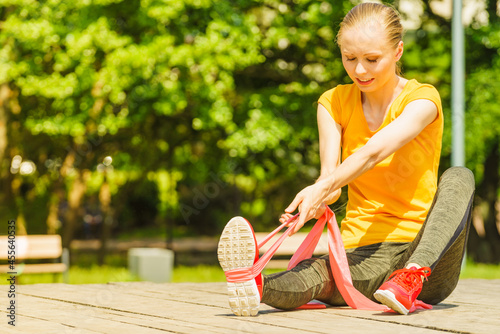 Girl doing exercise outdoor, using resistance fit band. photo