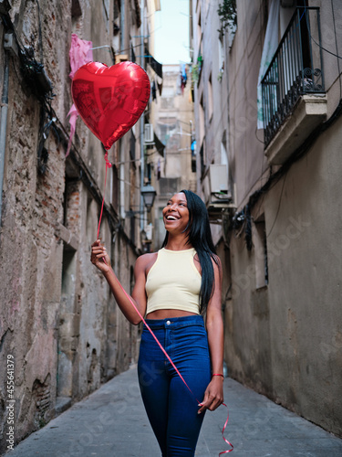 Young woman with a heart-shaped balloon outdoors on the street.