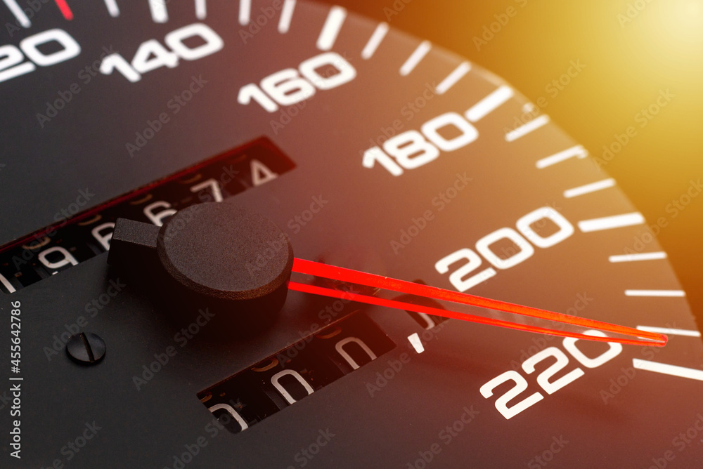 Fototapeta premium Car speedometer. Auto car speedometer shows 220 km h or miles.Closeup shot,dark black background.Automobile dangerous speed concept