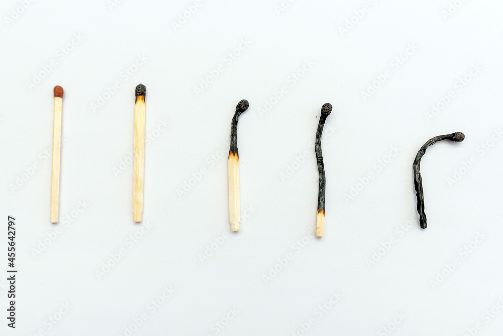Row of burnt matches and whole one on white background, top view,closeup. Concept of different phases in human life. Row of burnt matches and whole one on white background, top view,closeup. Concept of different phases in human life.