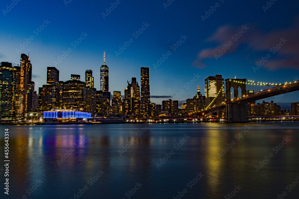 Stupenda vista notturna dello skyline di New York dal Brooklyn Bridge Park , Manhattan, New York. Fiume con palazzi illuminati come sfondo. Foto Panoramica in lunga esposizione.