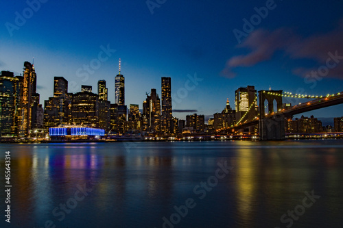 Stupenda vista notturna dello skyline di New York dal Brooklyn Bridge Park , Manhattan, New York. Fiume con palazzi illuminati come sfondo. Foto Panoramica in lunga esposizione.