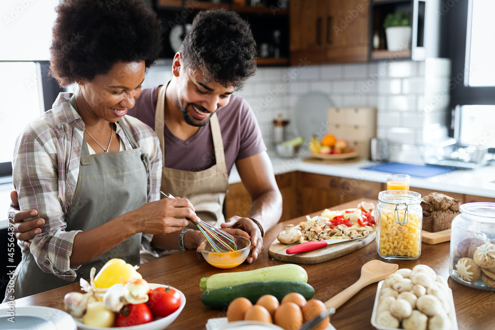 Beautiful young couple is talking and smiling while cooking in kitchen at home. Beautiful young couple is talking and smiling while cooking in kitchen at home.