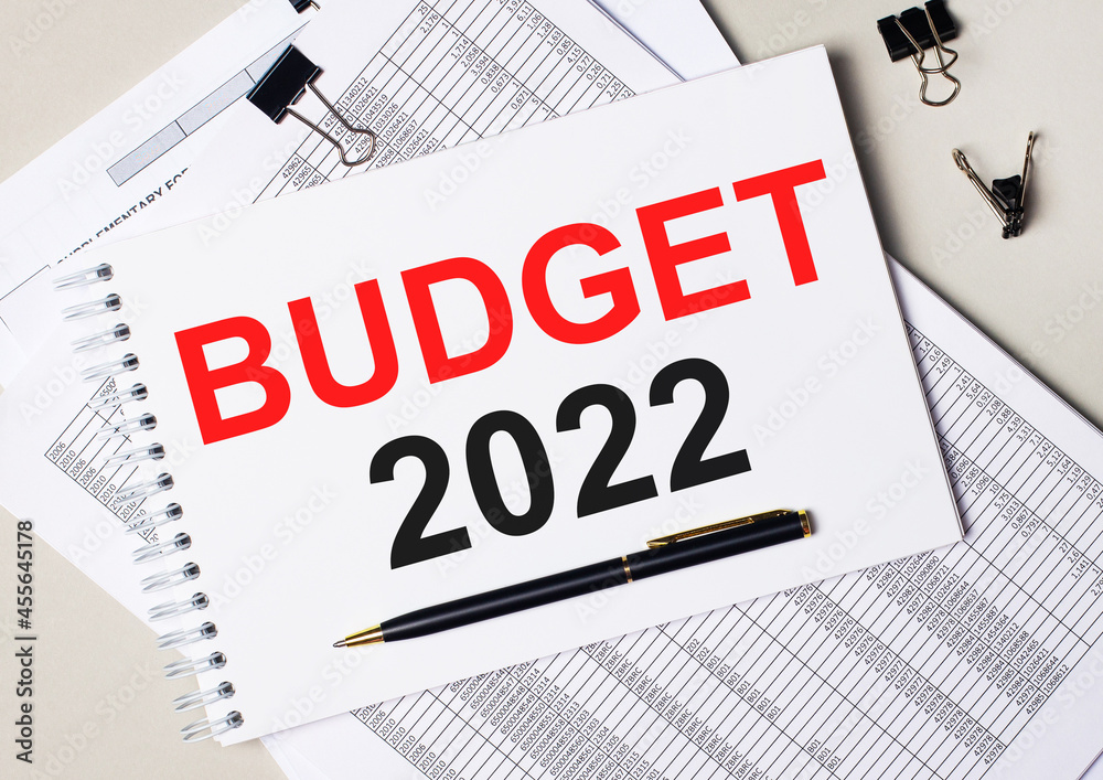 On the desktop there are documents, pen, black paper clips and a notebook with the text BUDGET 2022. Business concept On the desktop there are documents, pen, black paper clips and a notebook with the text BUDGET 2022. Business concept