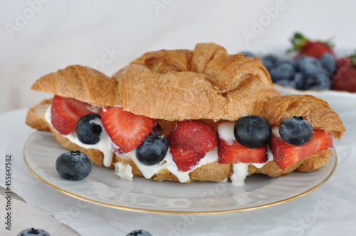 fresh croissant with cream, strawberries and blueberries