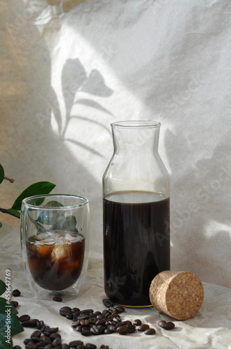 fresh iced black coffee in a glass with coffee beans and green  leaves