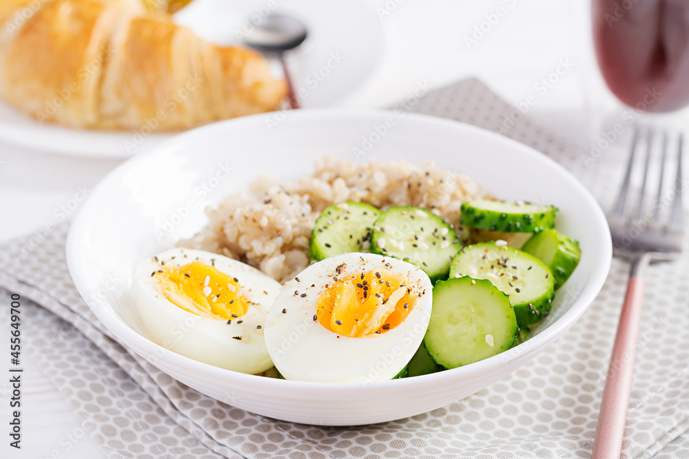Breakfast oatmeal porridge with boiled egg, cucumber and sesame seed. Healthy balanced food. Breakfast oatmeal porridge with boiled egg, cucumber and sesame seed. Healthy balanced food.