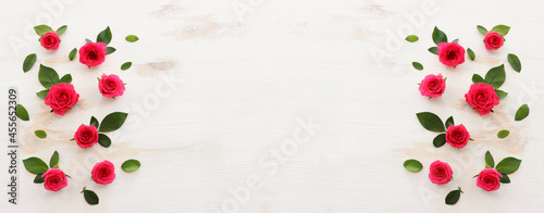 White wooden delicate background with pink roses and petals. Top view
