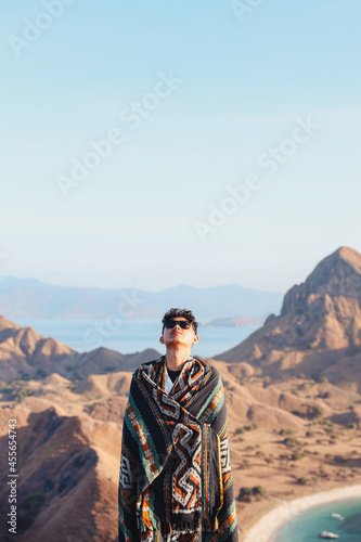Asian man enjoying fresh air wearing Indonesia traditional fabric called kain songket on top of Padar Island