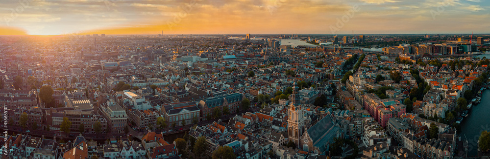 Beautiful evening panorama of Amstedam city looking towards the west with beautiful sunset and sun setting down over Amsterdam. Drone view.