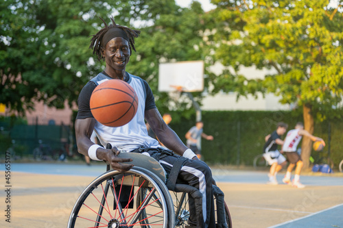 African man with a disability caused by polio playing basketball, champion athlete having disability in a wheelchair, concept of determination and mental toughness photo