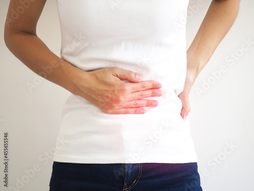 Asian woman suffering from abdominal pain due to chronic inflammatory bowel disease. closeup photo, blurred. photo
