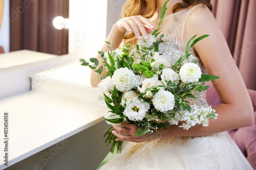 bride holding wedding bouquet close-up indoors. hands hold wedding bouquet close up 